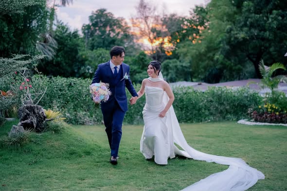 Newlyweds walking together through a garden at sunset