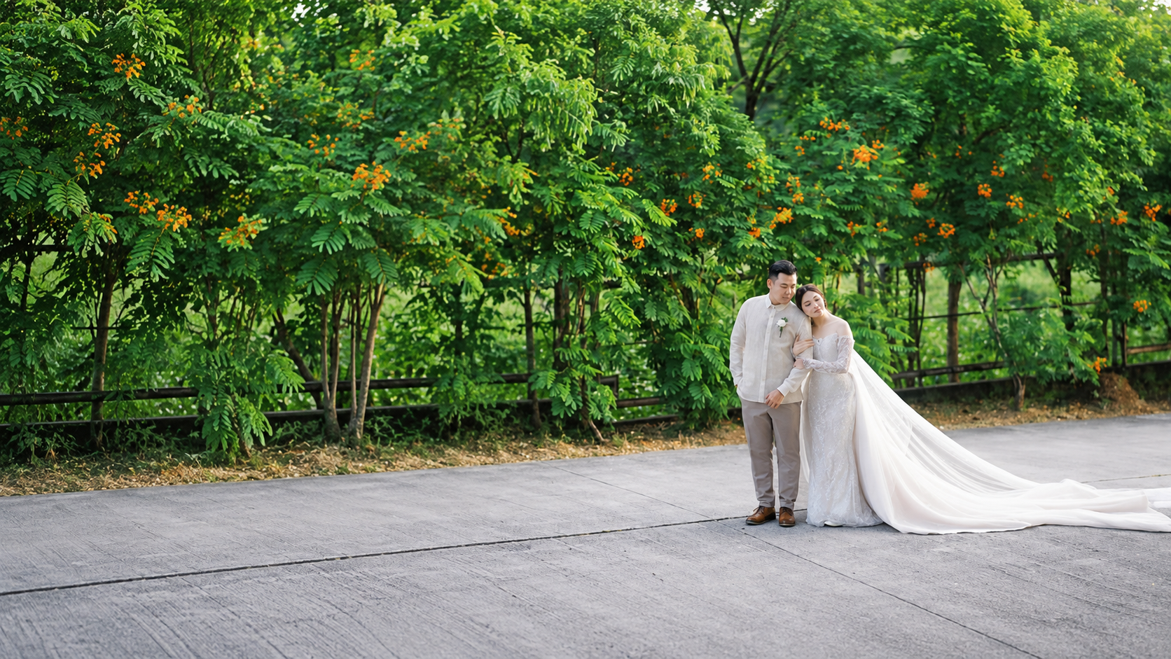 Newlyweds sharing a quiet moment beneath green trees
