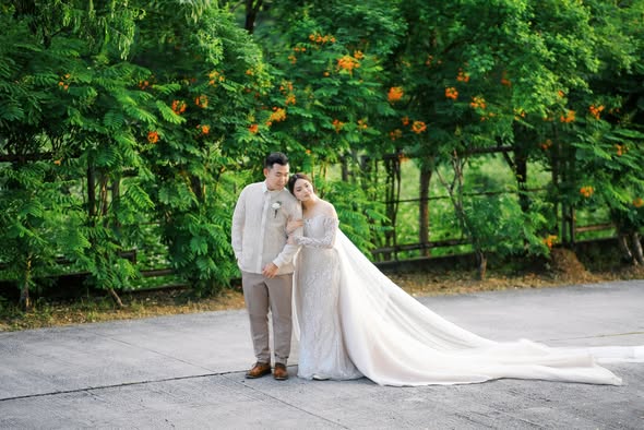 Newlyweds sharing a quiet moment beneath green trees