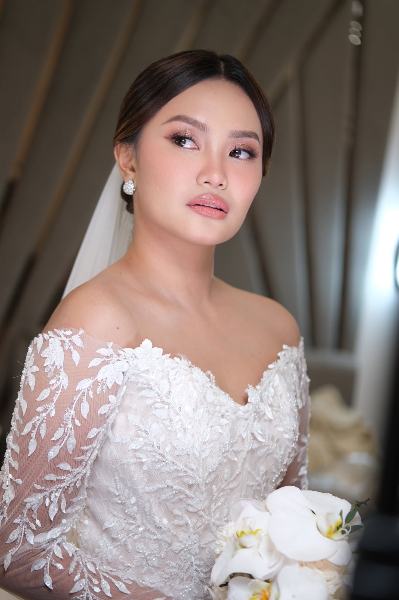 Kiara in an embroidered wedding gown holding white orchids